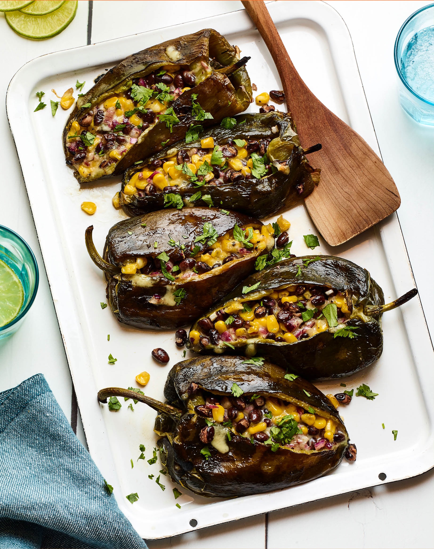 Grilled Stuffed Poblano Peppers on a white plate and blue surrounding